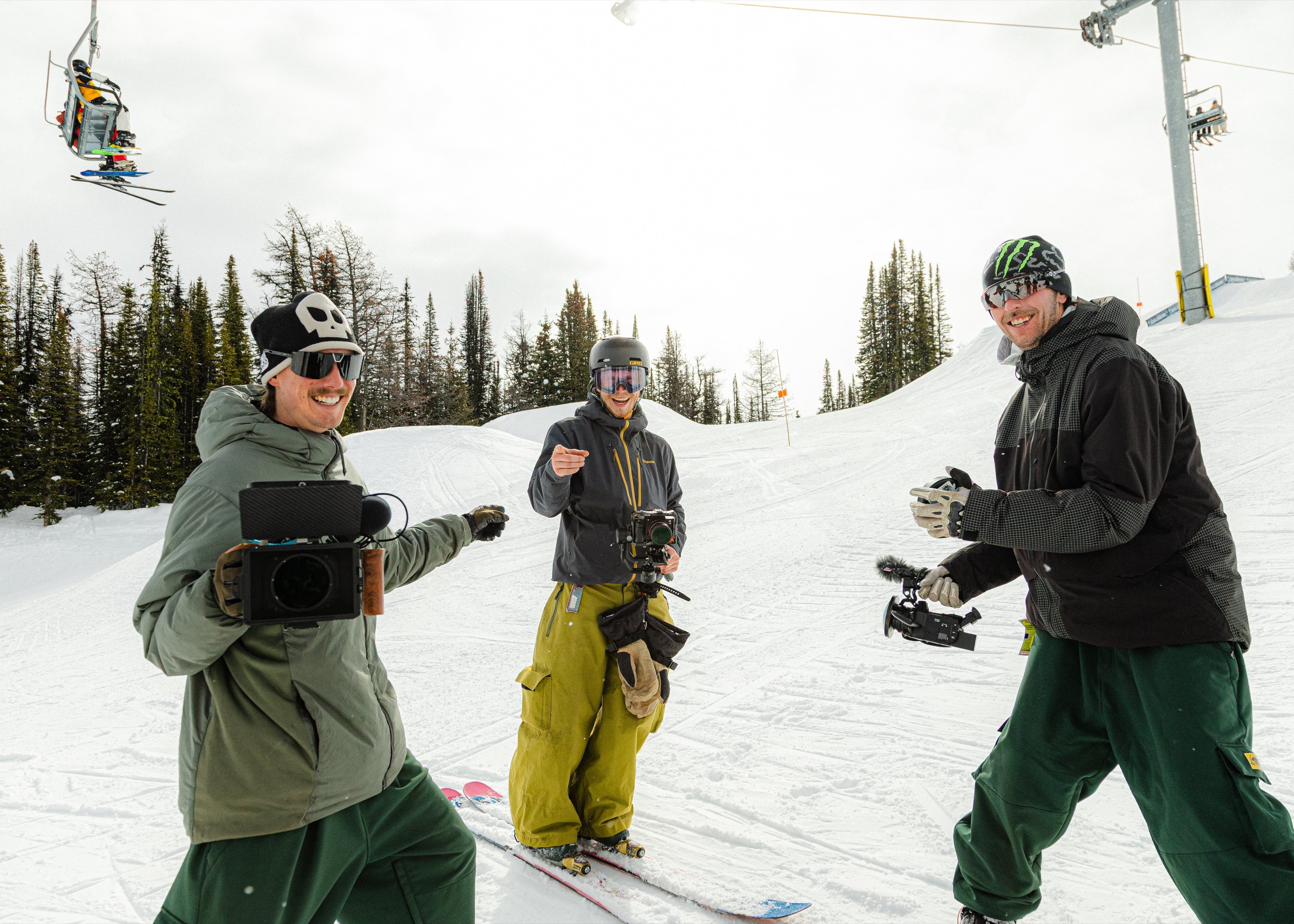 Three camera operators working together on a snowy mountain