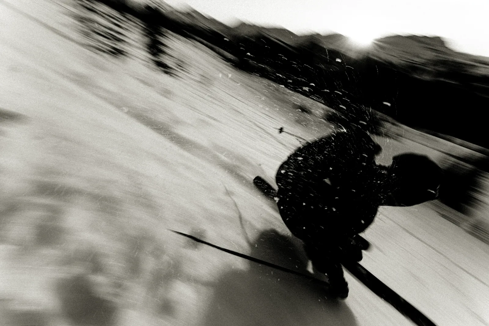 A skier carving across a snowy slope in black and white
