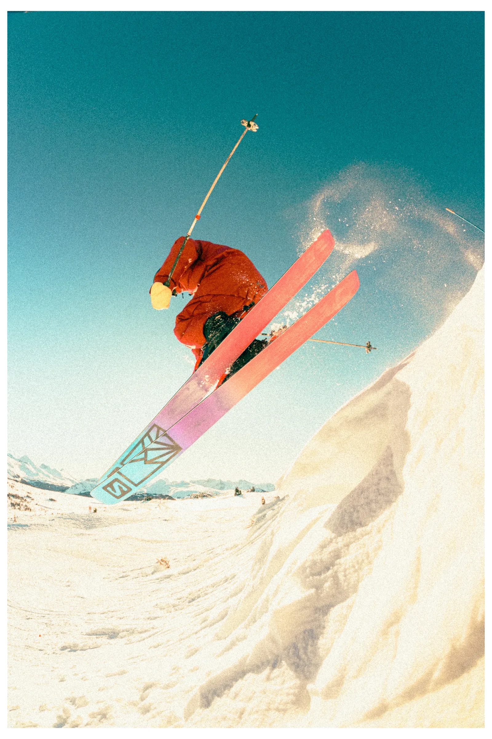 A skier crossing above the camera with bright skis