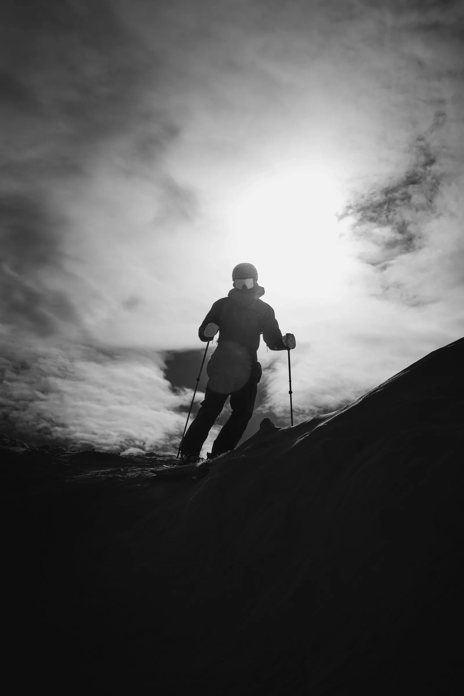 A skier climbing toward a bright winter sky
