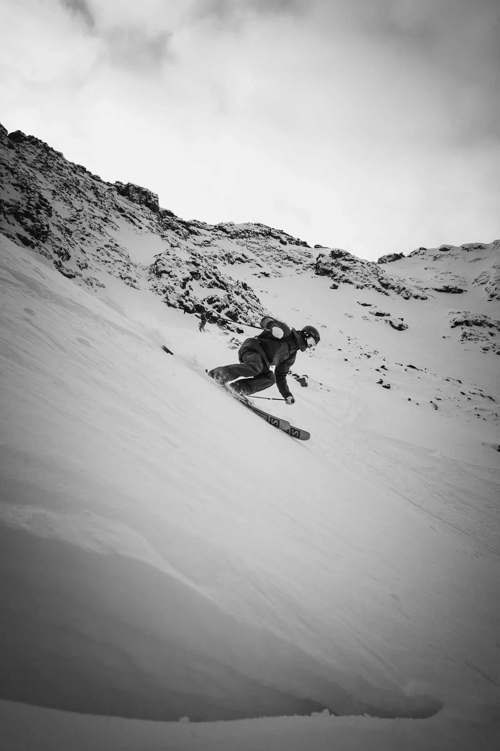A skier moving below a clouded mountain ridge