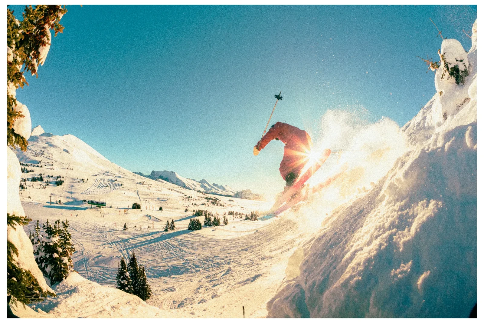 A skier throwing snow into warm alpine light