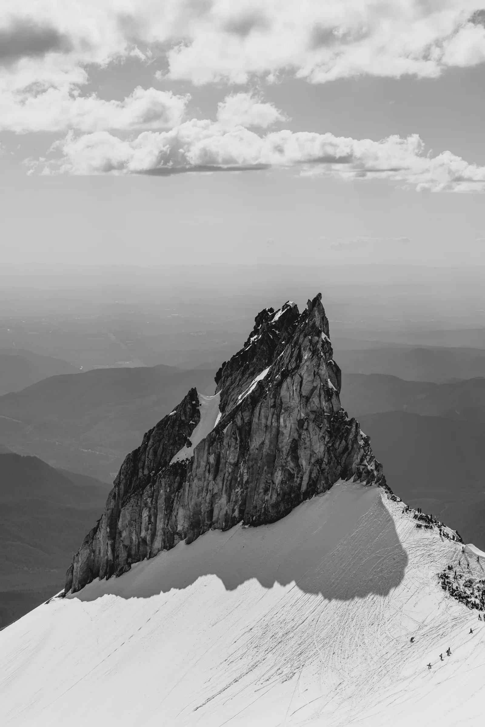 A rock spire above the snow in black and white