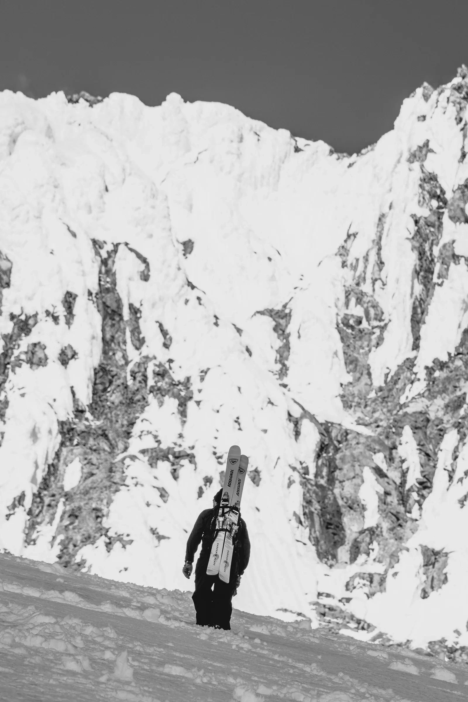 A person framed against a dark rock wall