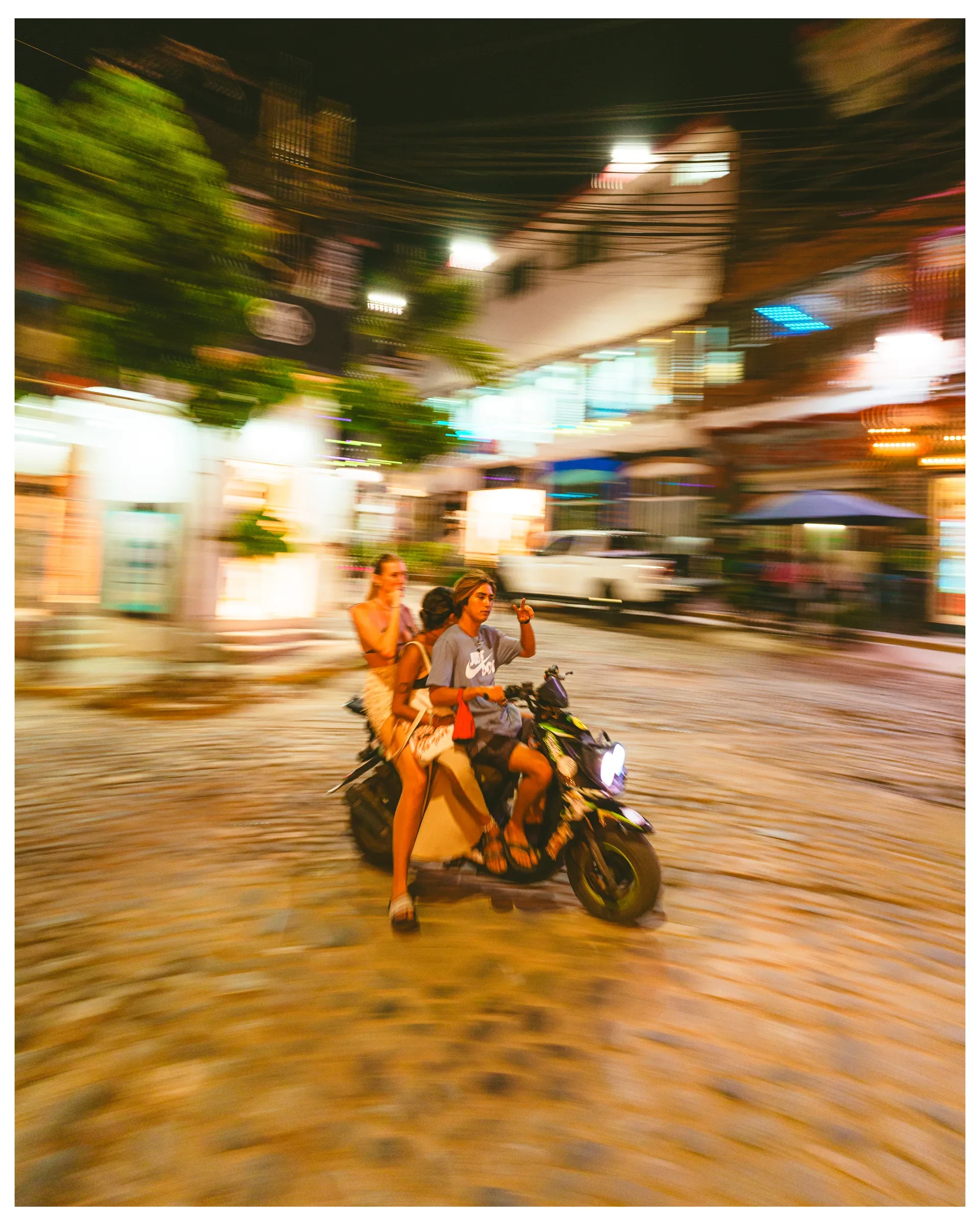 A motorcycle moving through a lit street at night