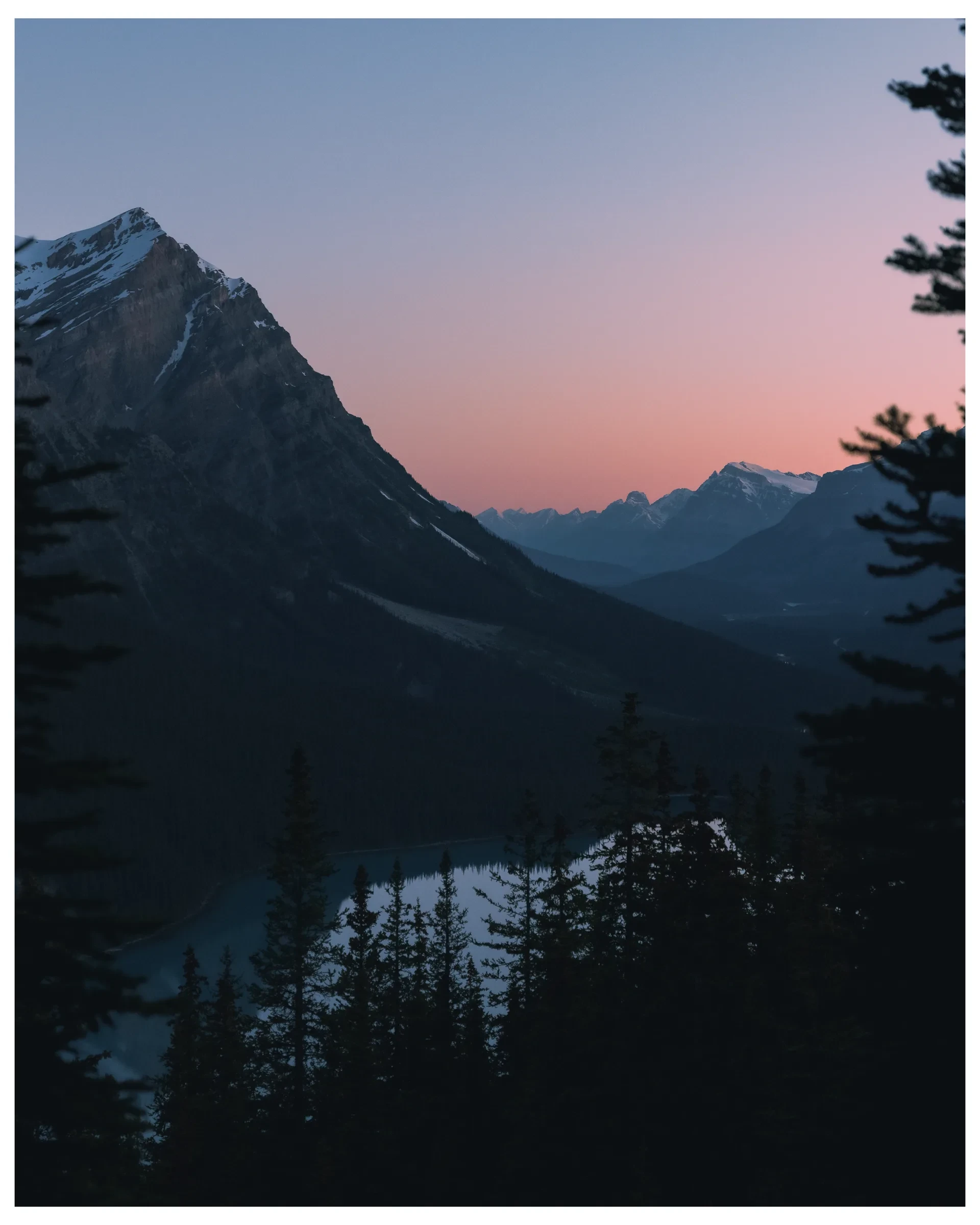 A figure above a mountain lake after sunset