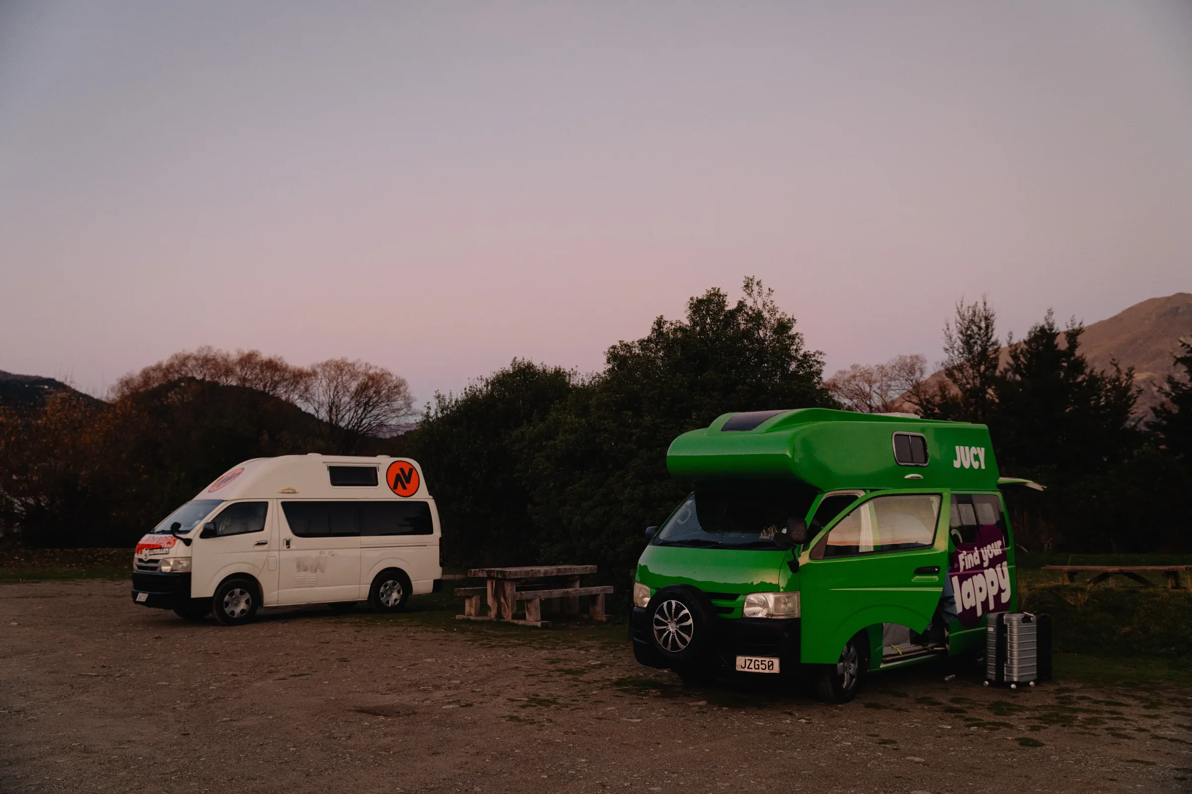 Camper vans parked beneath evening light