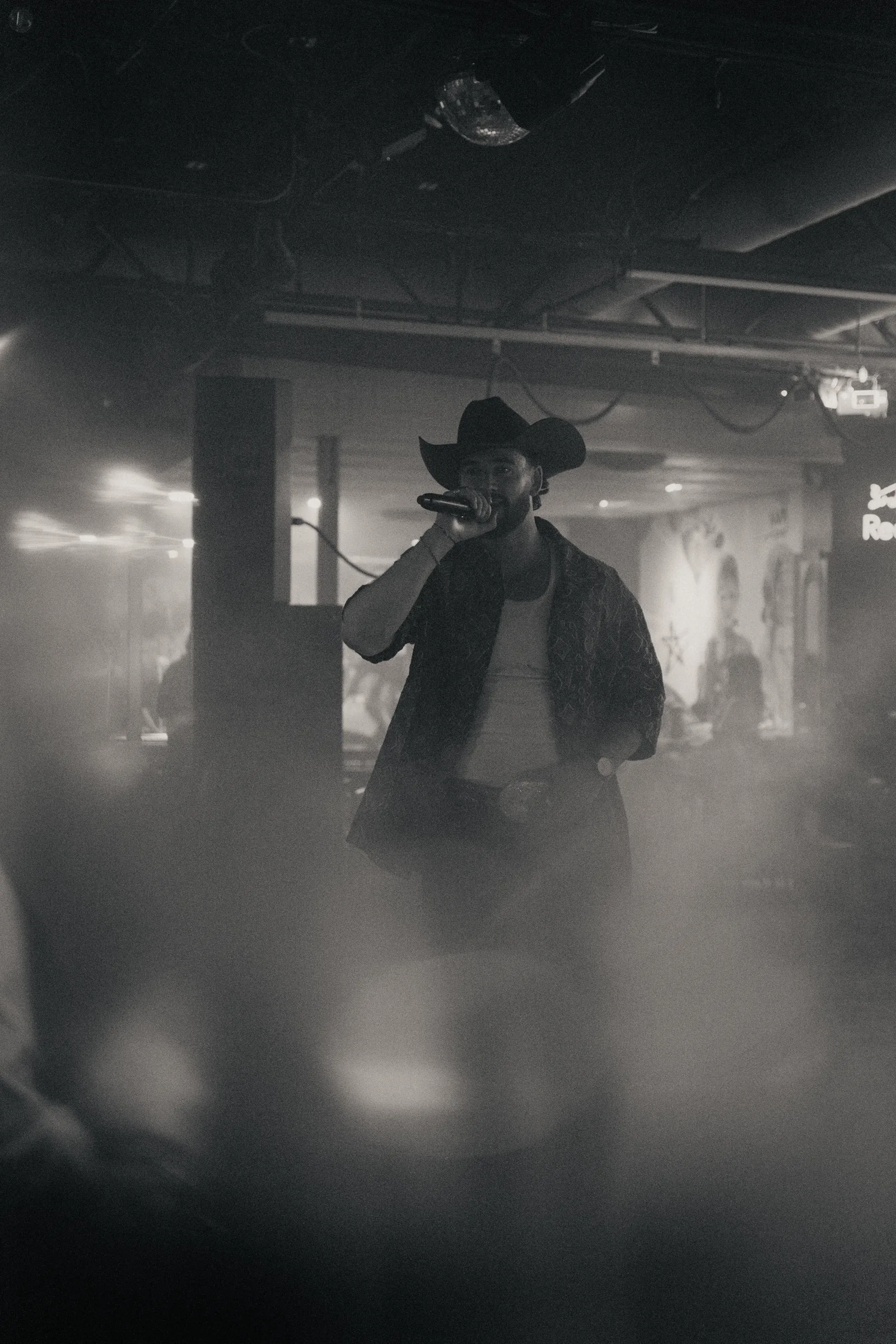 A performer framed in stage haze in black and white