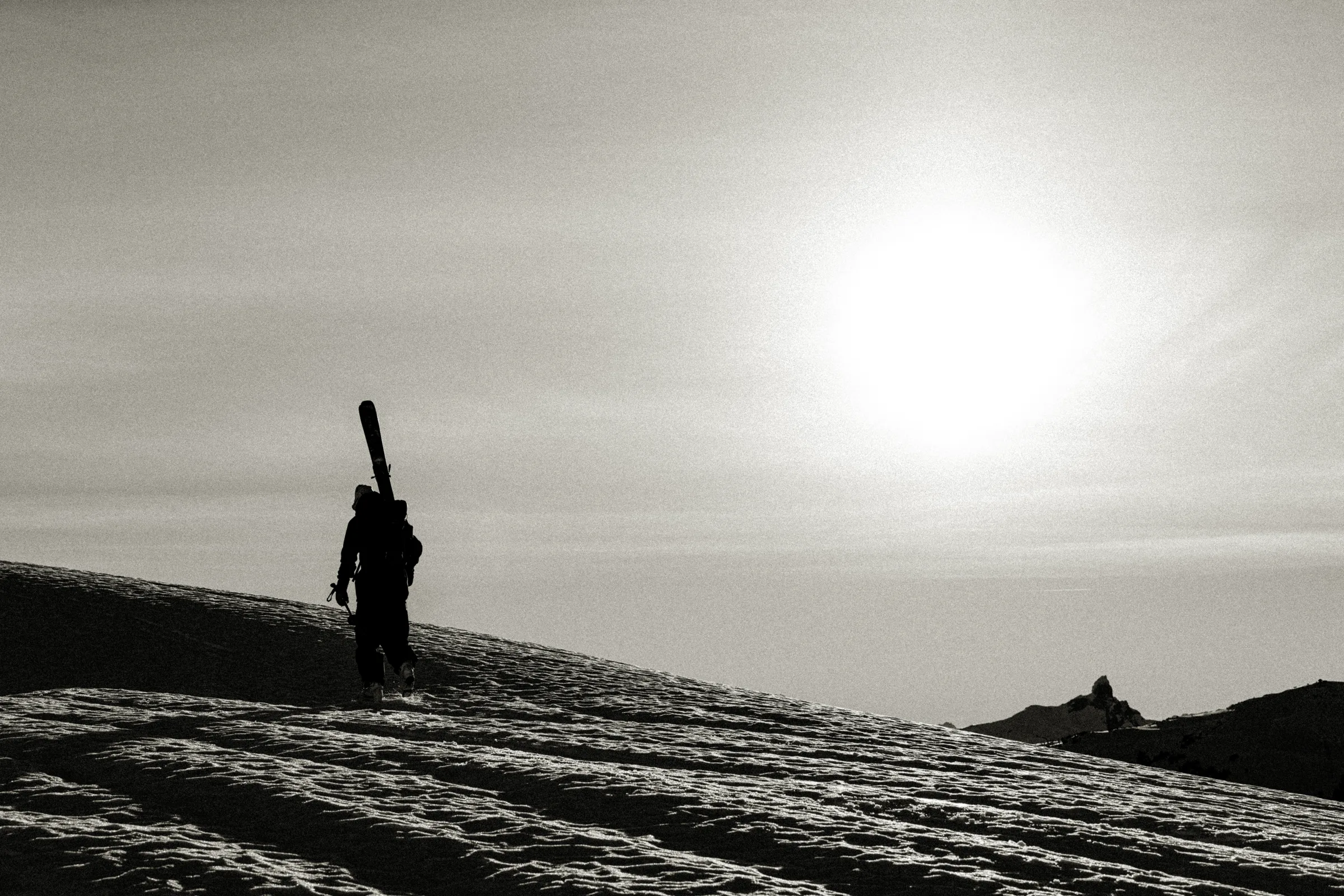 A lone figure standing against a bright mountain horizon