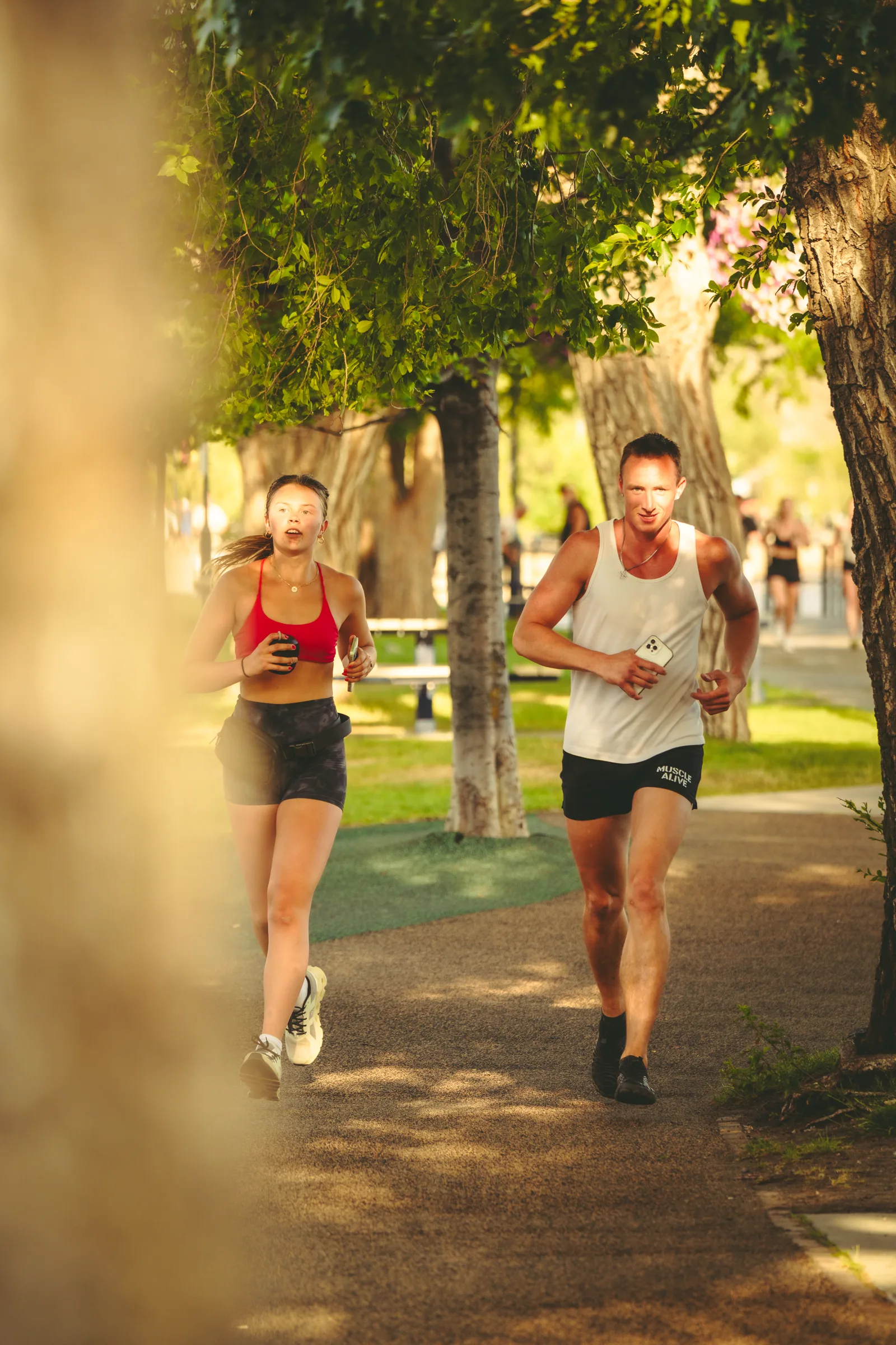 Two runners on a shaded park path