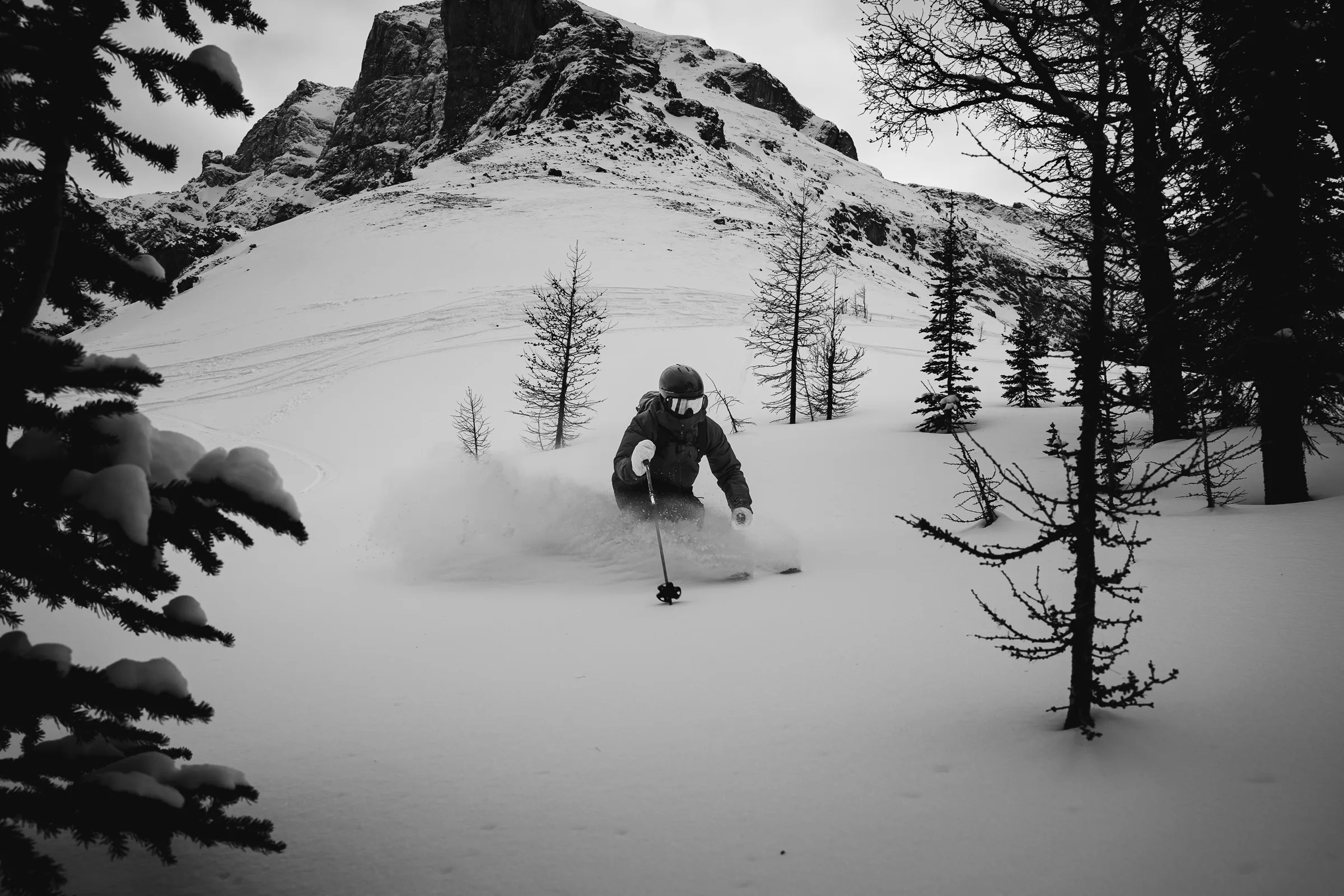 A skier moving through an open alpine bowl in black and white