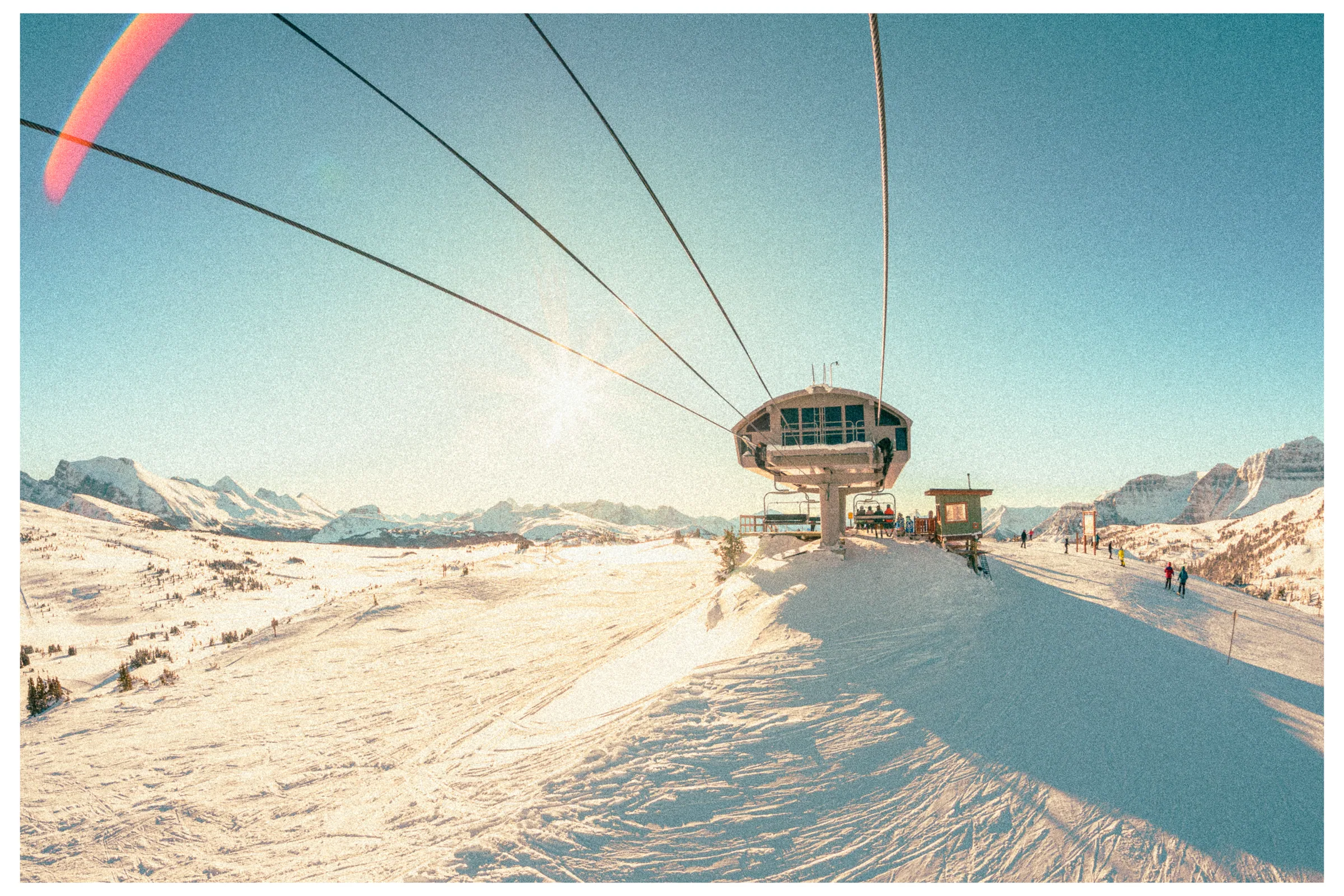 A skier riding a chairlift across an open mountain face