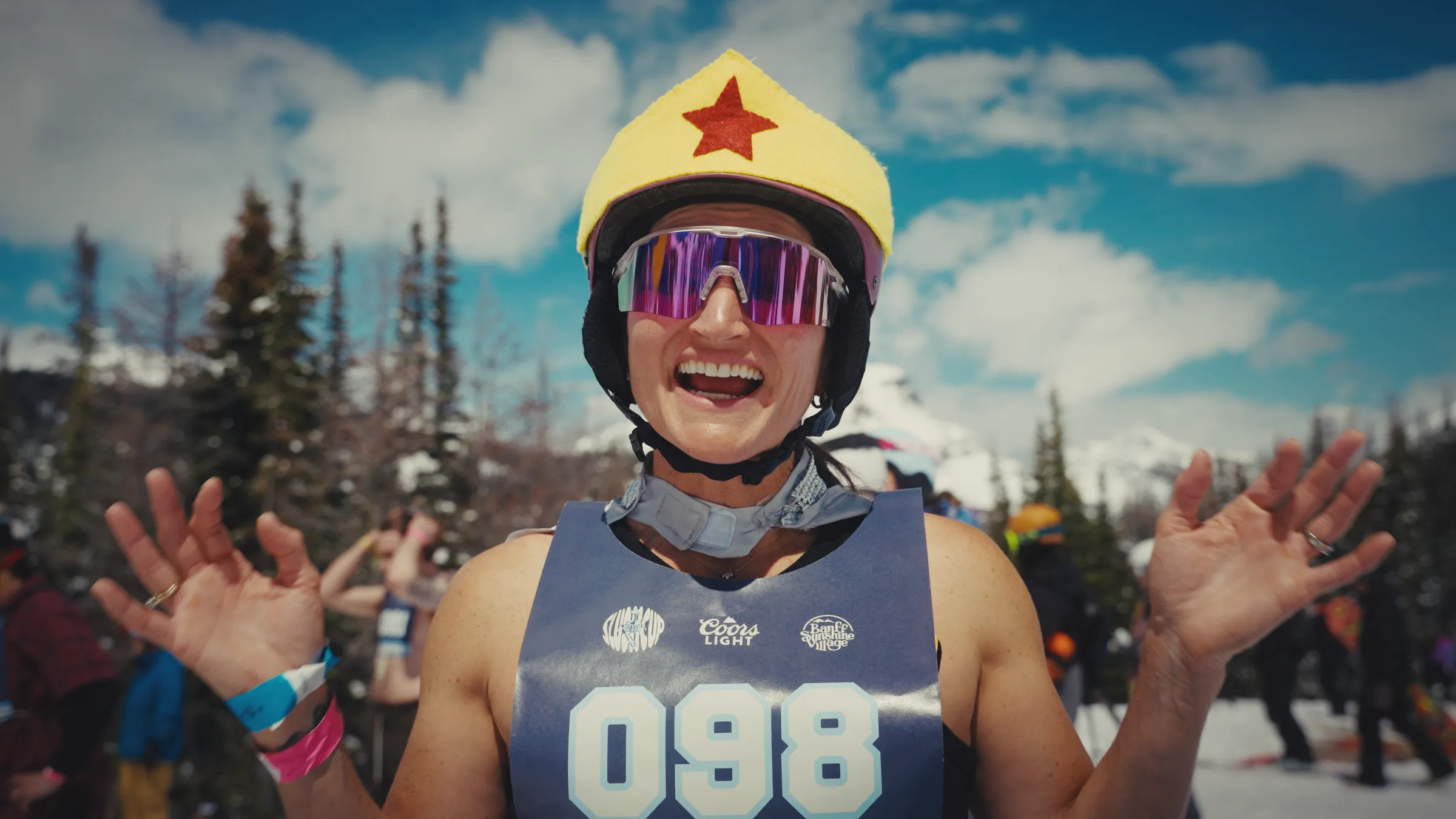 A costumed Slush Cup competitor smiling with both hands raised