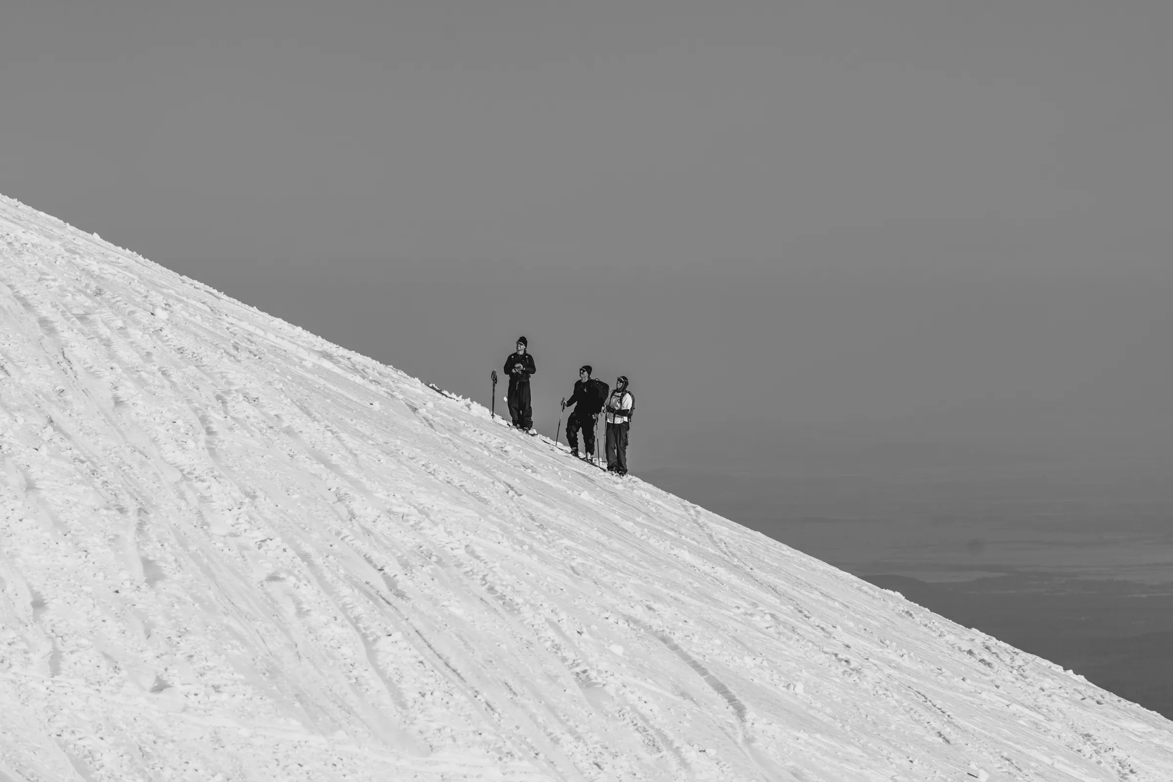 Two figures crossing a broad snow ridge