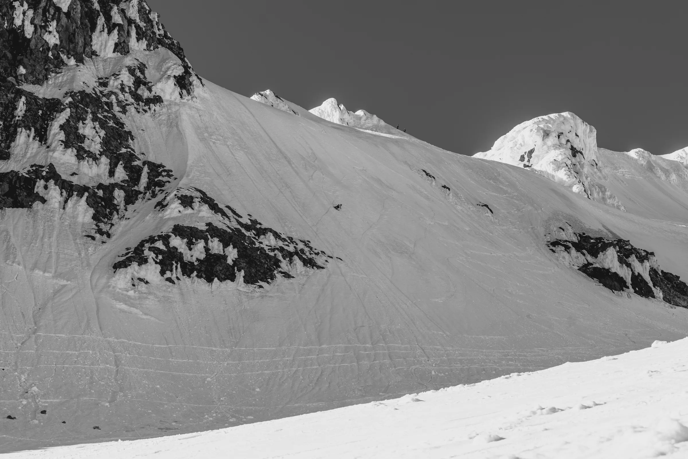A small group crossing a high open snow ridge